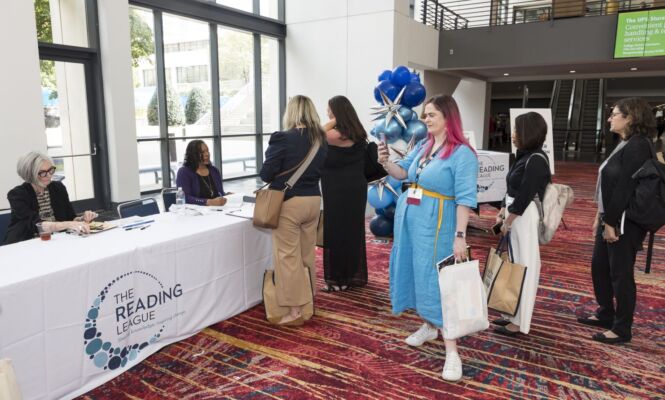 Two authors signing books for a group of conference attendees